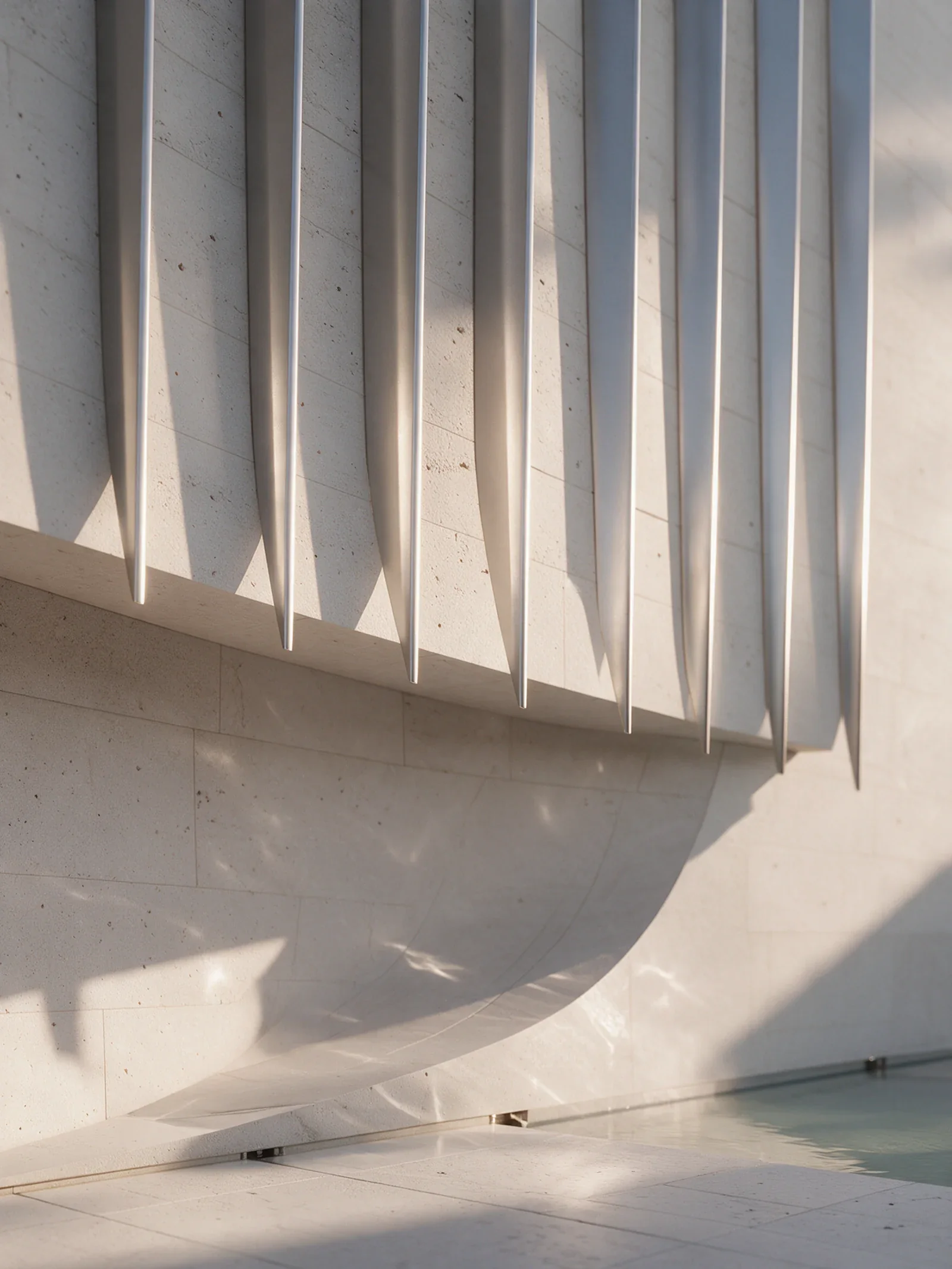 A close view: fine metal edges above porous stone, a curved surface and water at its foot.